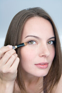 Young woman applying eye shadow, portrait, close-up