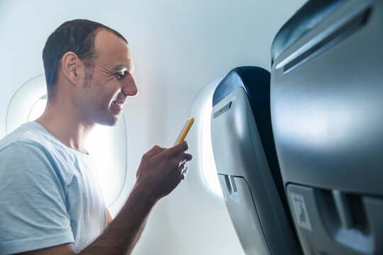 Smiling male passenger uses a smartphone during a flight