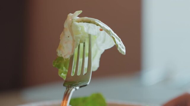 Crisp romaine lettuce on fork closeup, soft bokeh kitchen background, fresh olive oil drizzle and cracked pepper, vibrant green textures, minimalist mood for gourmet food styling, slow cinematic pan.