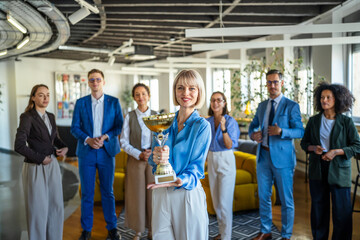 Business team celebrating achievement with winning trophy and award