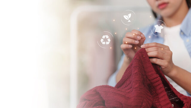 Woman sewing red sweater with recycling icons for sustainable fashion and repair concept
