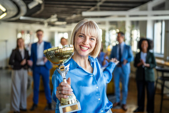 Businesswoman celebrating success winning a golden trophy