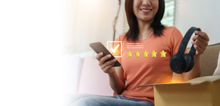 Smiling Asian woman holding headphones and smartphone for product review rating