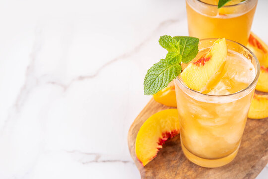 Summer cold drink, peach iced tea slushie cocktail. Shaved ice non-alcohol cold beverage, peach juice infused tea, copy space