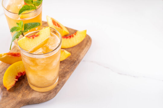 Summer cold drink, peach iced tea slushie cocktail. Shaved ice non-alcohol cold beverage, peach juice infused tea, copy space