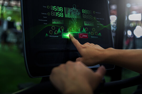 Cropped hand pressing start button on treadmill console for fitness workout
