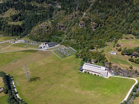 Aerial view of Wasserkraftwerk Robbia hydroelectric power plant situated in a green valley with power lines and infrastructure in Poschiavo, Grisons, Switzerland.