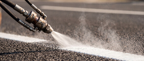 Obraz premium Road line painting with thermal paint sprayer applying white road marking on asphalt