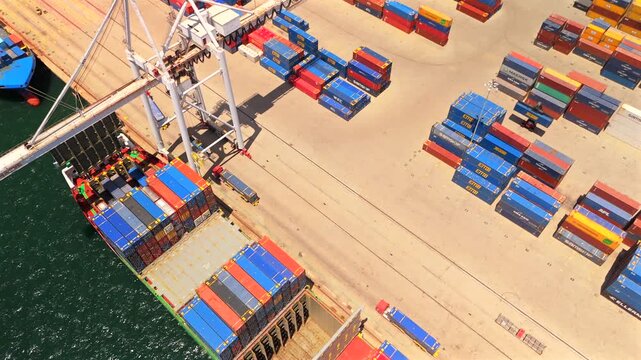 Сontainer ship moored at a commercial terminal with colorful shipping containers, quay cranes, cargo handling equipment and industrial port logistics