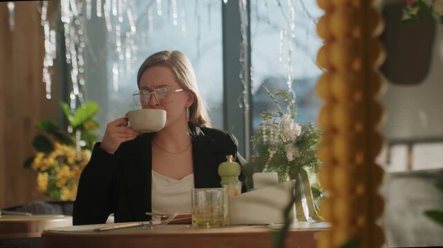Woman examines coffee. Indoor view of woman inspecting coffee. Bright interior captures woman analyzing steaming beverage. Woman scrutinizes freshly brewed cup of hot coffee indoors