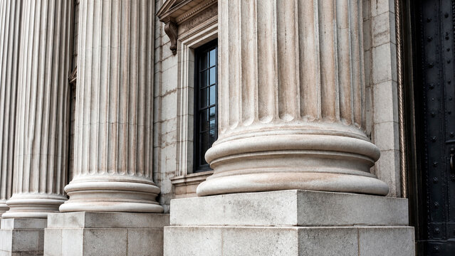 Classical stone pillars of courthouse building. Architectural detail of ionic column facade. Exterior view of government bank institution or museum. Concept of stability and law.