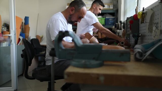 Two technicians collaborating on prosthetic arm in workshop