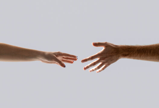 Helping hand gesture composition isolated over gray background. Closeup two hands reaching to each other. Concept for salvation, rescue, friendship, guidance, help, helping
