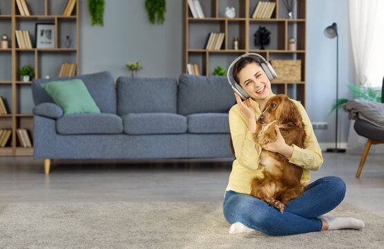 Woman with dog and headphones enjoying music. At home the owner hugs a cocker spaniel on the carpet, sharing affection for lifestyle and pet care uses. Clear warm pet bonding concept.
