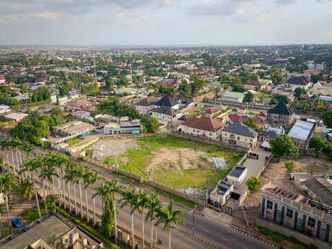 Aerial view of Isa Kaita Road lined with palm trees, residential houses, and an empty plot of land in Nasarawa, Kaduna, Nigeria.