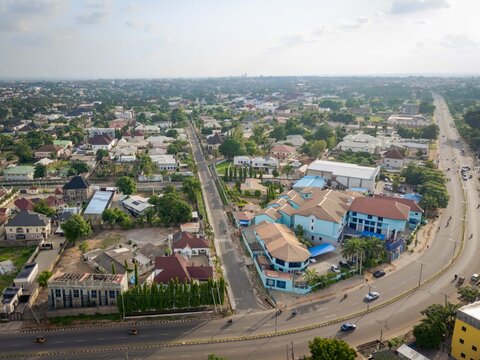 Aerial view of Isa Kaita Road featuring urban residential buildings, lush trees, and traffic on the main thoroughfare in Nasarawa, Kaduna, Nigeria.