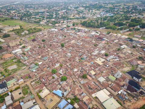 Aerial view of the dense urban landscape along Isa Kaita Road, featuring numerous corrugated metal rooftops, narrow streets, and scattered trees in Nasarawa, Kaduna, Nigeria.