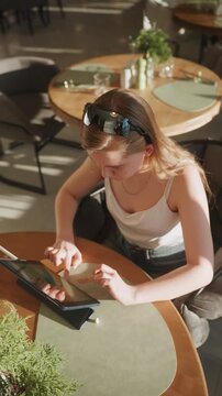 Focused white designer prototyping on tablet interactive interface testing with precise finger input, stylus resting, modern cafe workspace, bright directional light, concentrated expression