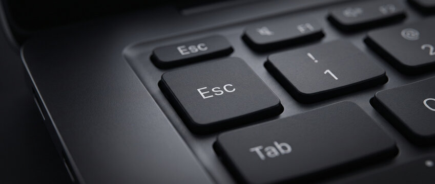 Macro Close Up of ESC Key on Modern Laptop Keyboard with Soft Cyan Backlight