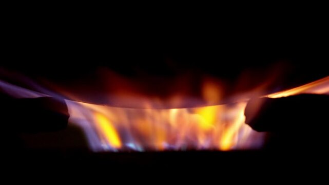 A mesmerizing close-up of dancing flames captured in stunning 4K slow motion. The fire flickers and flows against a dark background, revealing beautiful orange, yellow, and blue flame details.