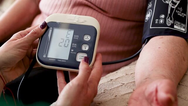 Nurse measuring blood pressure of elderly woman at home. Home healthcare visit, geriatric care, senior health monitoring, aging in place, medical assistance concept