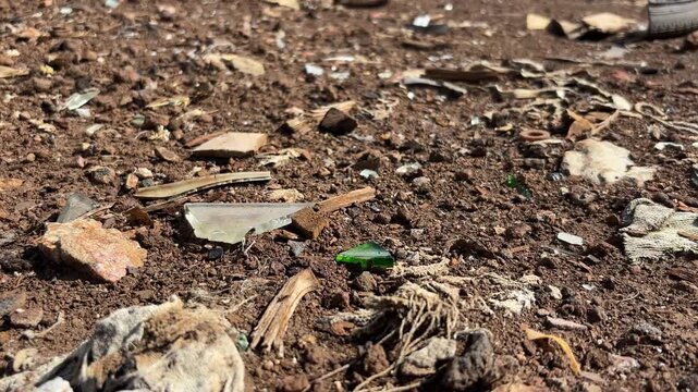 Close-up of broken glass fragments and debris on polluted soil