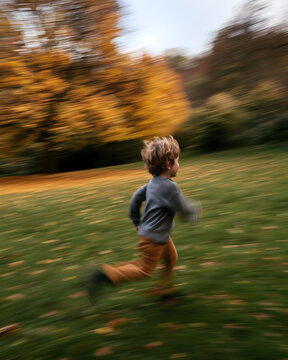 Child running joyfully through autumn park with motion blur
