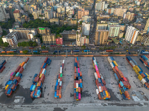 Aerial view of a busy container terminal with rows of colorful shipping containers and urban buildings in the background in Dhaka, Dhaka Division, Bangladesh.