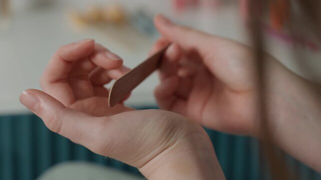 Intimate nail grooming. Soothing home wellness activity involving soft lighting and gentle buffing. Peaceful moment of selfcare featuring delicate nail smoothing under warm ambient light
