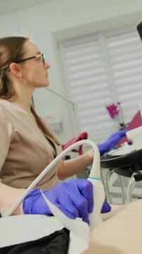 Gynecologist performs pelvic ultrasound during clinic examination. Doctor guides transducer steadily following scan details on monitor