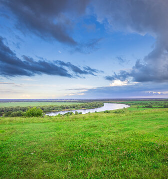 Vast green fields stretch toward a winding river
