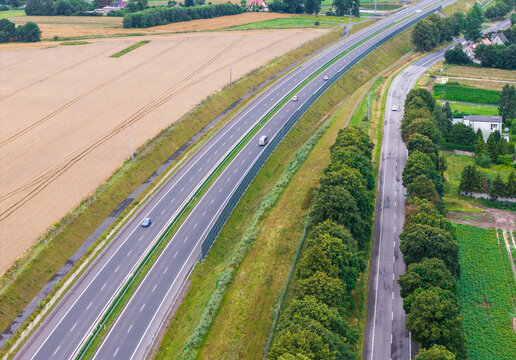 Aerial view of the Droga Ekspresowa S6 highway with vehicles traveling through agricultural fields and green surroundings in Slupsk, Pomeranian Voivodeship, Poland.