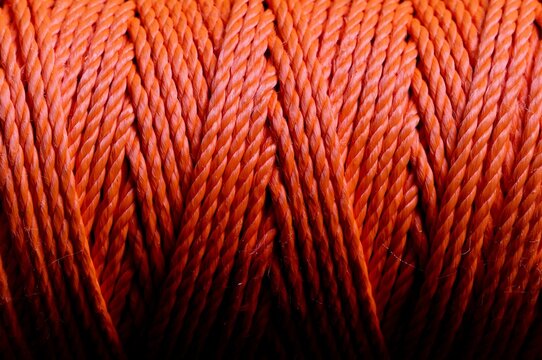 Macro close up of thick orange woven rope fibers with orange colored, material