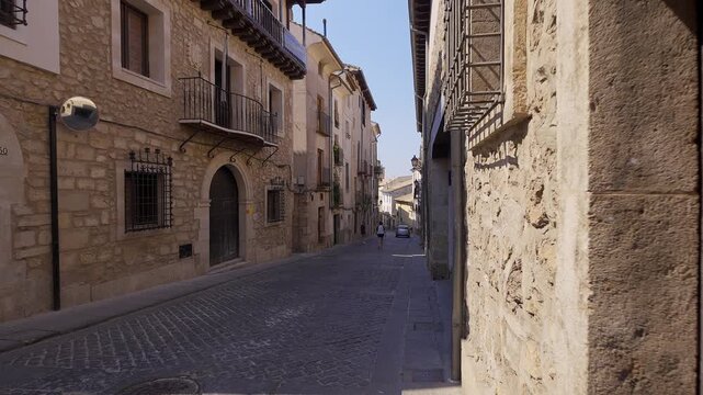 Historic stone houses and pedestrians along Calle San Pedro in the old town of Cuenca Spain