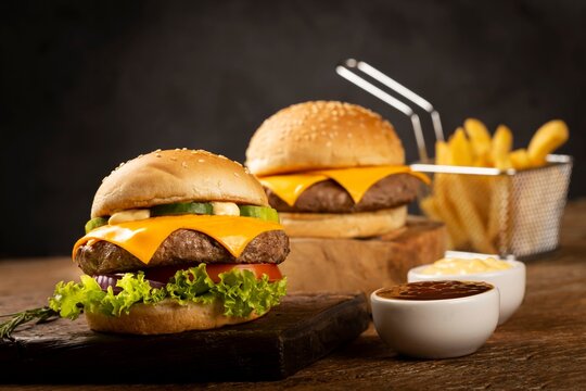 Two cheeseburgers with french fries and dips on wooden surface cheeseburger sandwich delicious culinary