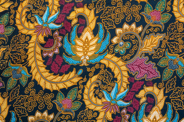 Fototapeta premium Traditional Indonesian batik pattern featuring intricate floral motifs and organic shapes in a vibrant blend of gold, blue, and magenta. 