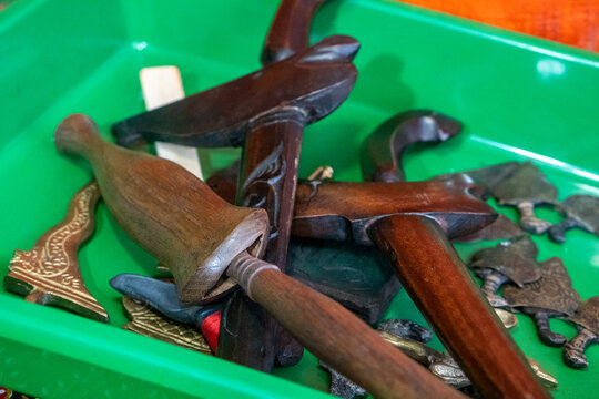 Green tray holds a Keris a traditional, asymmetrical Indonesian thrusting weapon complete with its wooden sheath or Wrangka and hilt alongside several detached metal blade components Tosan aji. 