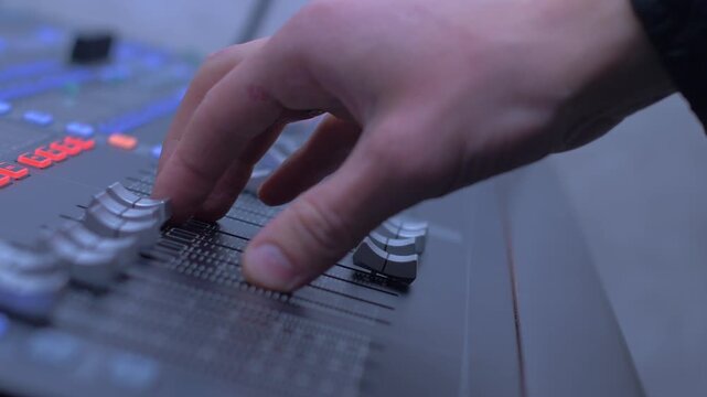 Close up of hand moving audio mixer fader
