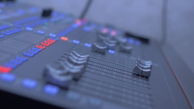 Hand adjusting multiple faders on sound mixer