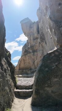 Rugged sandstone rock formations under a bright blue sky with wispy clouds, showcasing natural geological textures, outdoor adventure and travel background