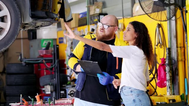 Professional mechanic and customer discussing vehicle repair in garage collaborative automobile maintenance expert explaining car to client