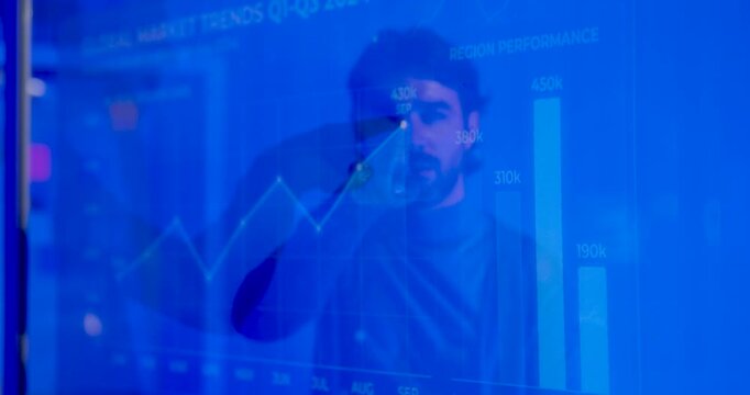 Adult male business professional studies transparent market dashboard, touches face and reviews growth charts while analyzing performance data for digital business intelligence and strategy planning.