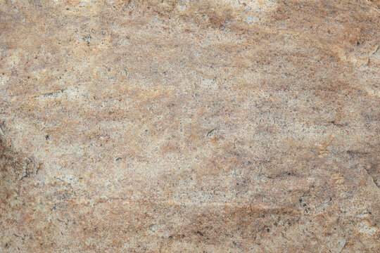 Close-up of a smooth travertine surface with warm beige hues, fine grain, and delicate veining; sparse dark specks add organic contrast, highlighting the stone's natural character