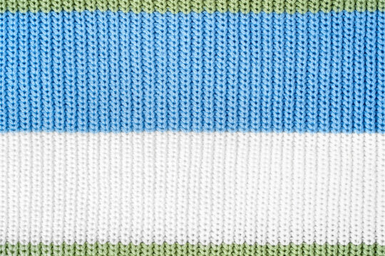 Close-up sweater texture with green, blue and white color stripes, showing knitted surface and soft textile detail. Concept of tactile material structure and biosynthetic, sustainable recycled fabric