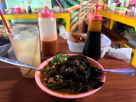 Indonesian Mie Ayam Bakso topping with wood ear mushrooms, served with iced drink and condiments.