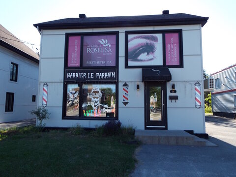 Gatineau, Quebec, Canada &ndash; June 16, 2026: Two blue recycling bins sit in the foreground below a tall business sign advertising "Roselisa Lashes and a barber shop" on Boulevard Gr&eacute;ber.