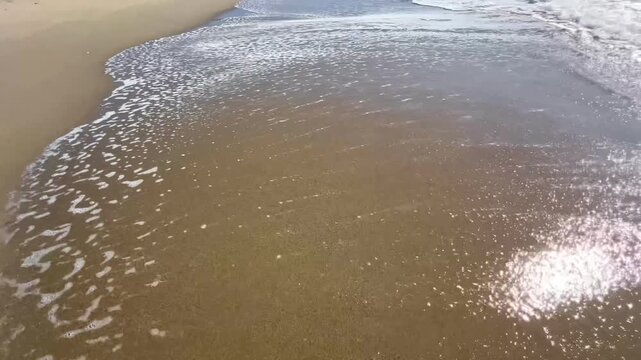 Woman feet walking on the shoreline of a long beautiful empty sandy beach in summer.