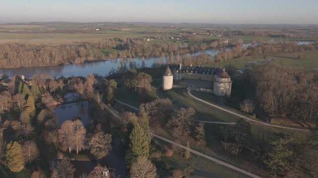 An aerial view shows a small turreted chateau with conical roofs beside a bend in the Loire River.