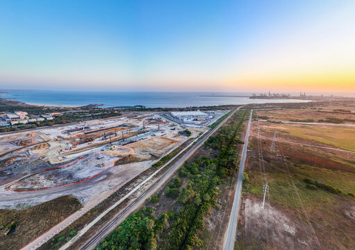Aerial view of the industrial port area, data center and construction site in Sines, featuring coastal terrain, railway tracks, and the Atlantic Ocean at sunset in Sines, Setubal, Portugal.