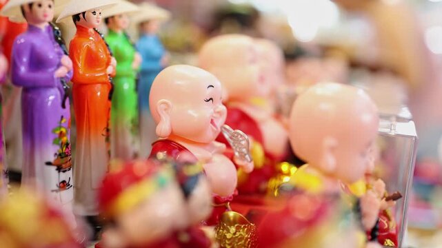 Traditional Vietnamese souvenirs and Buddha figurines displayed at gift shop in Nha Trang, Vietnam. Close up of colorful dolls in ao dai and laughing monk statues at souvenir stall.